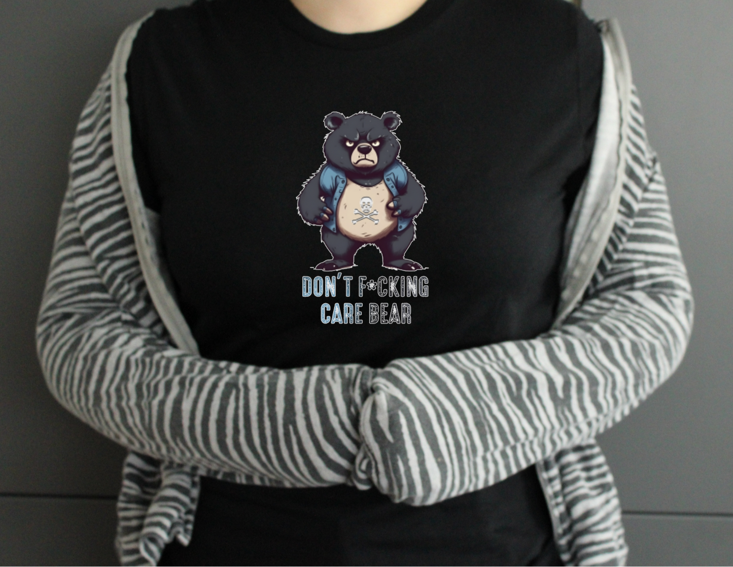 Person wearing a black hoodie with a graphic of a bear and text, over a striped sweater.