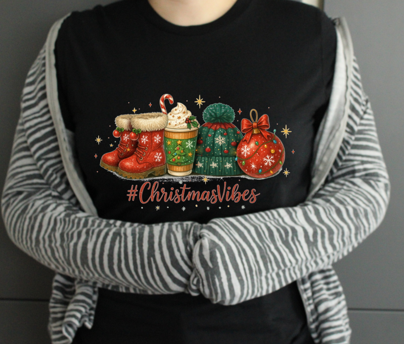 Person wearing a black tshirt with Christmas-themed design and '#ChristmasVibes' text.
