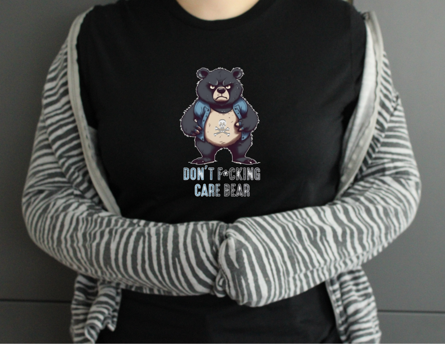 Person wearing a black hoodie with a graphic of a bear and text, over a striped sweater.