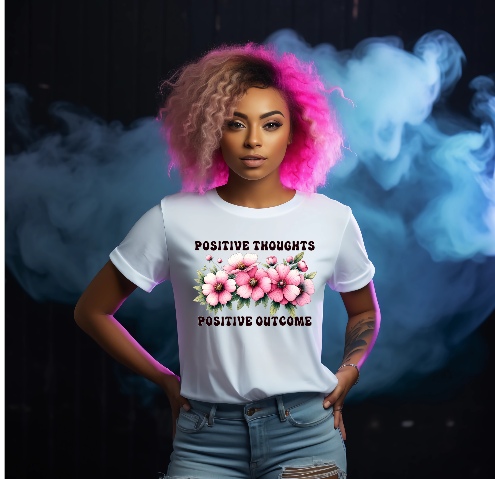 Person wearing a white t-shirt with floral design and text in front of a colourful smoke background with text saying positive thoughts
