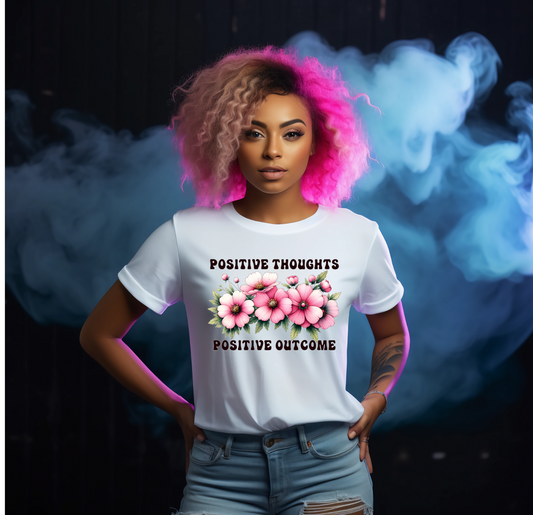 Person wearing a white t-shirt with floral design and text in front of a colourful smoke background with text saying positive thoughts