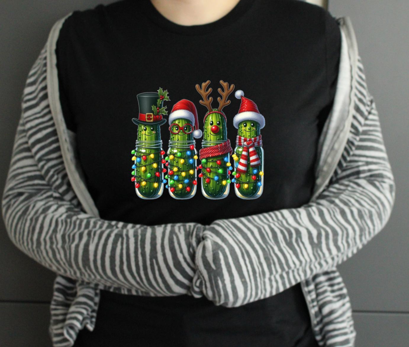 Person wearing a black tshirt with Christmas-themed design, standing against a neutral background