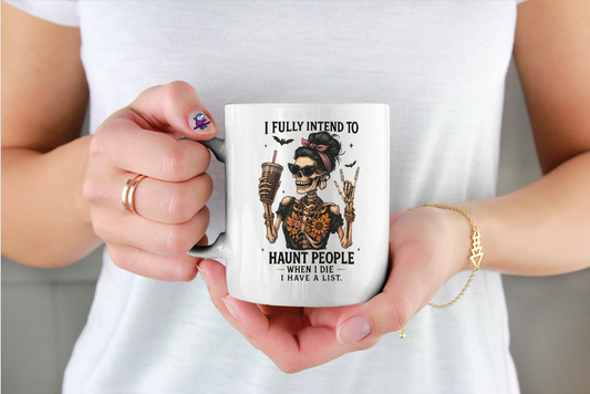 White mug with text saying "I Fully Intend To Haunt People When I Die I Have A List." skeleton image