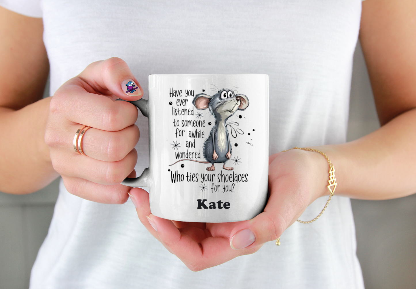 Person holding a mug with a cartoon character and text, wearing a white shirt.