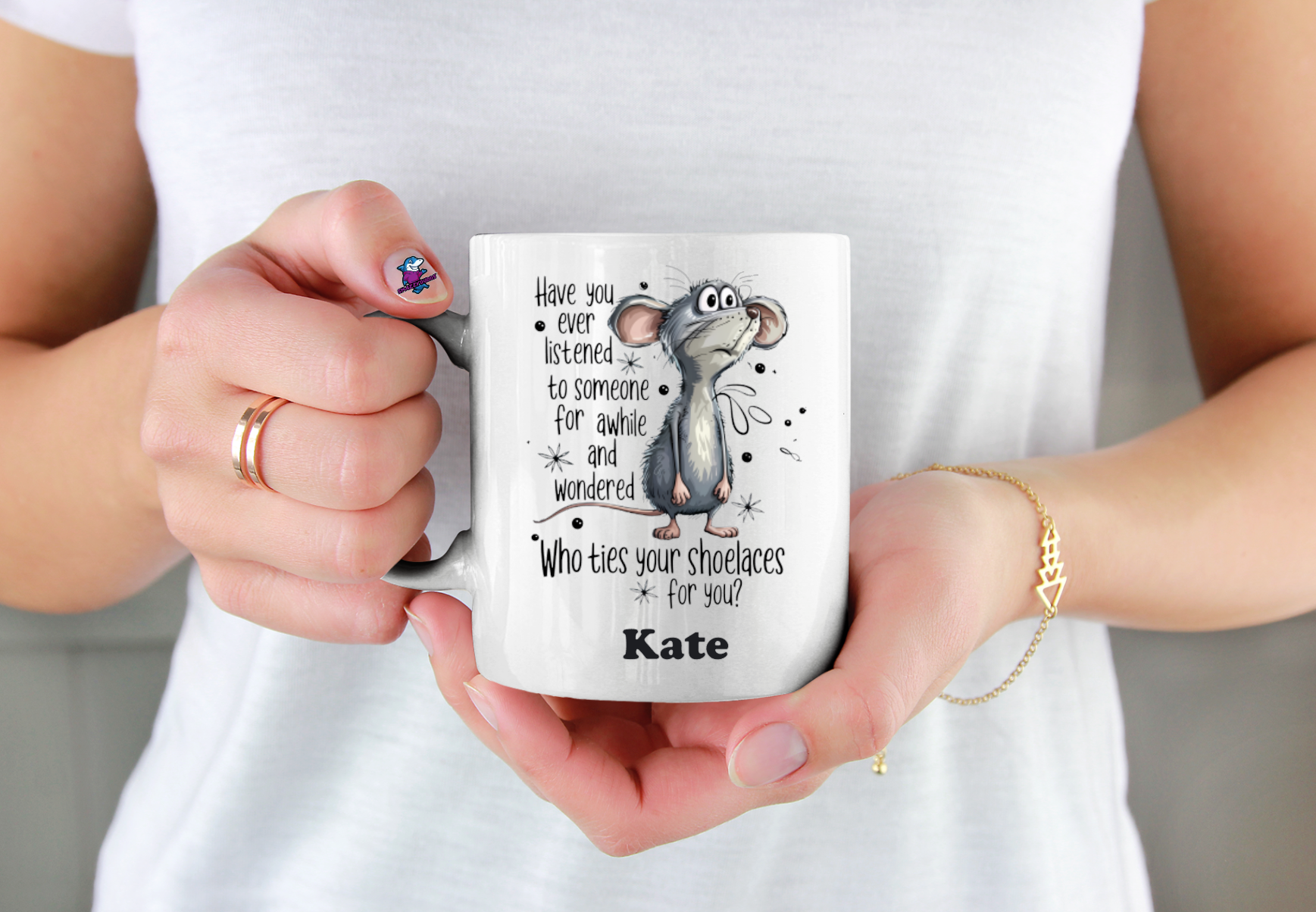 Person holding a mug with a cartoon character and text, wearing a white shirt.