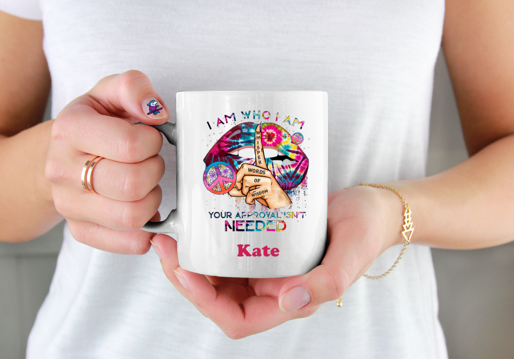 Person holding a mug with a colorful design and text, wearing a white shirt.