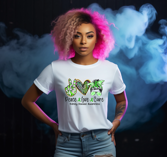 Woman wearing a white t-shirt with a colourful design and text, Peace Love Cure to support kidney disease awareness standing against a dark background with smoke effects.
