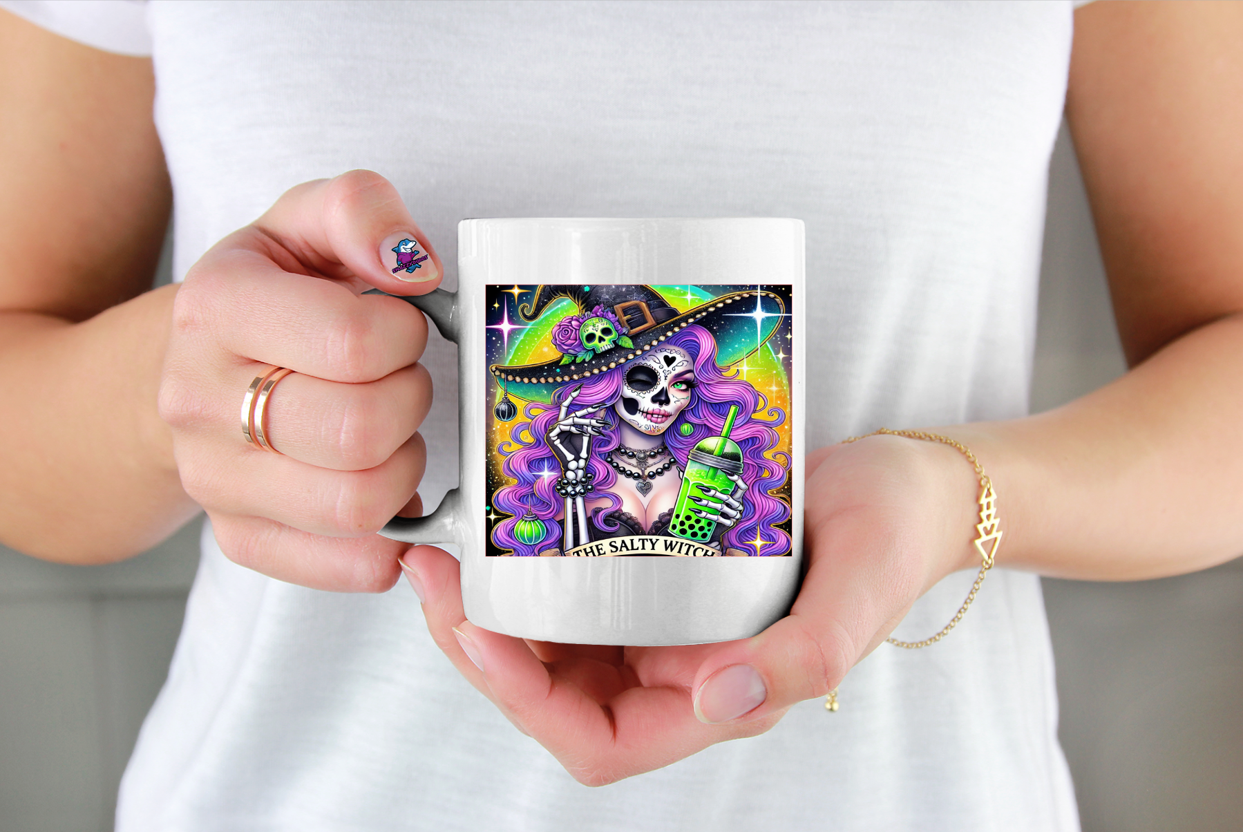 Person holding a mug with a colourful design featuring a skeleton and text saying The Salty Witch