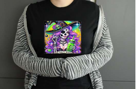 Person wearing a black tshirt with a colourful graphic design saying the salty witch