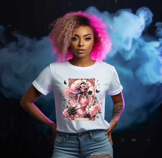 Person wearing a white t-shirt with a graphic wild rose tarot card witch design, standing against a dark background with smoke effects.