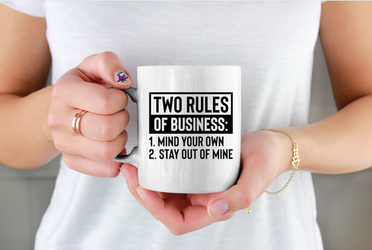 Person holding a mug with 'Two Rules of Business' text