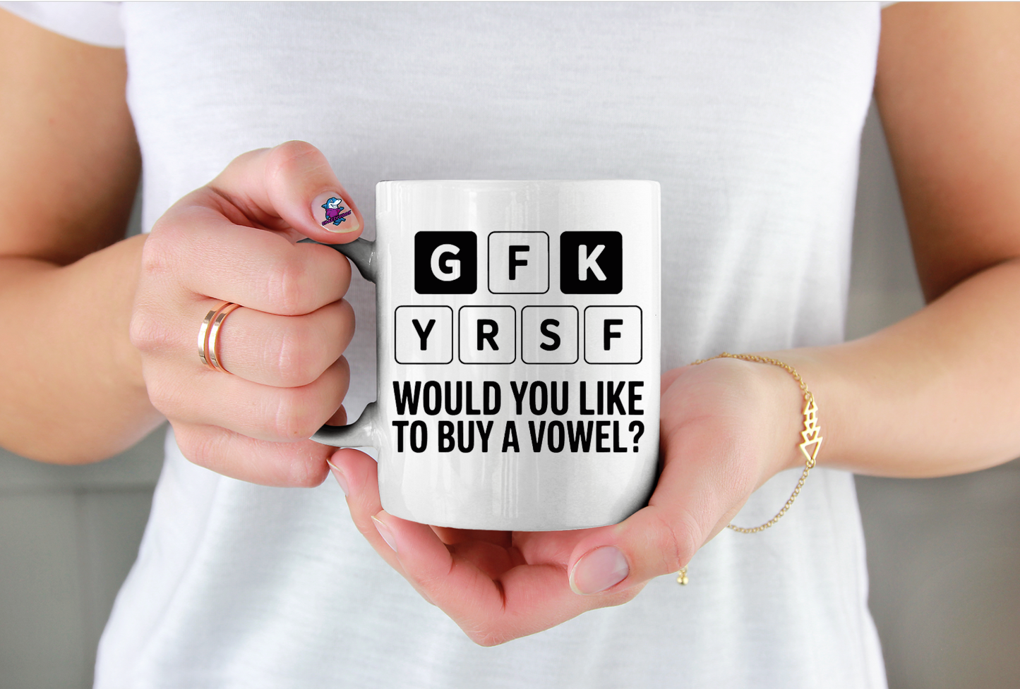 Person holding a white mug with text design, wearing a white shirt.