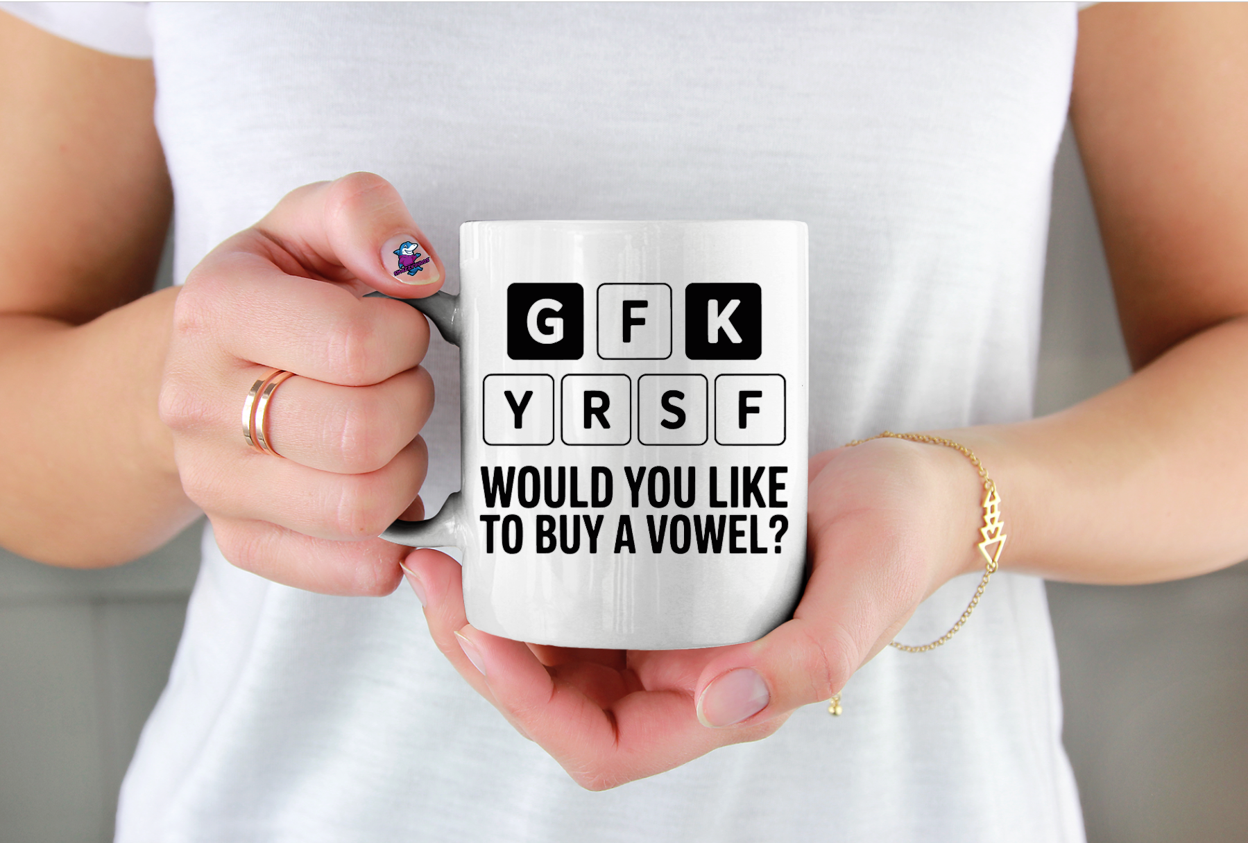 Person holding a white mug with text design, wearing a white shirt.