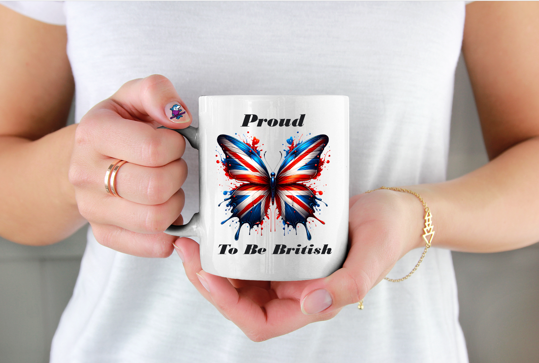Person holding a mug with a butterfly design and text 'Proud To Be British' against a white background